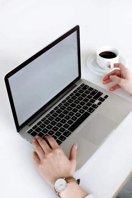 Woman in floral dress shopping online with a laptop and credit card indoors.